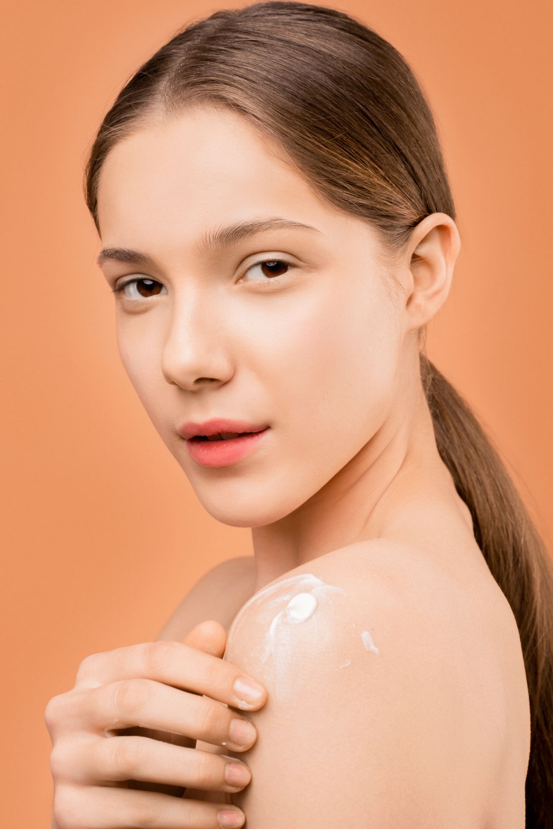 Woman applying moisturizer to her shoulder